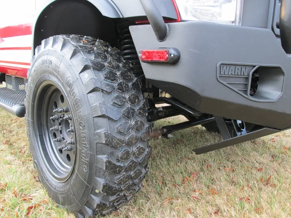 Exterior view of small fire truck showing cab, body compartments, and wheel/tire area.