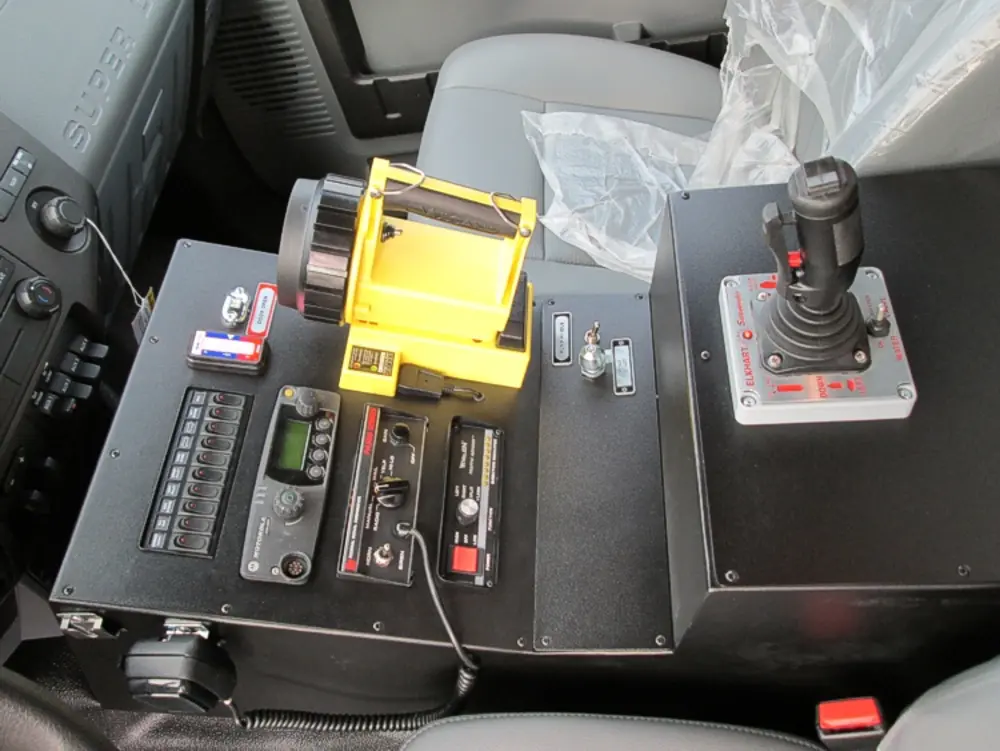 Exterior view of small fire truck showing cab, body compartments, and wheel/tire area.