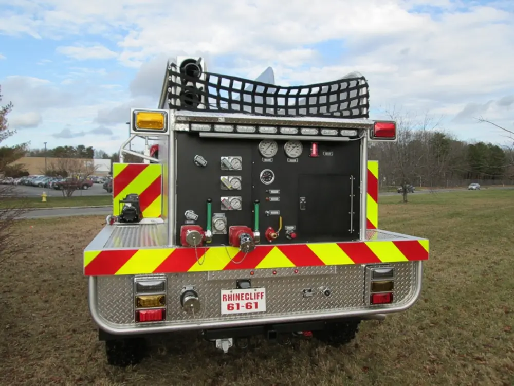 Exterior view of small fire truck showing cab, body compartments, and wheel/tire area.