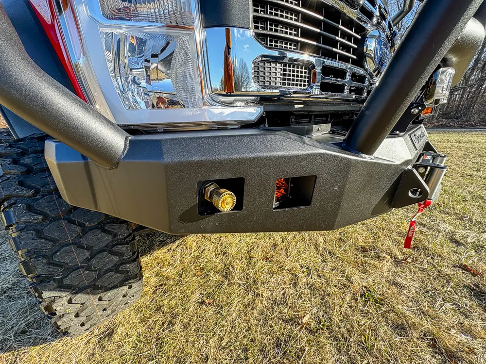 Front bumper corner close-up with brush guard and recessed outlet port.