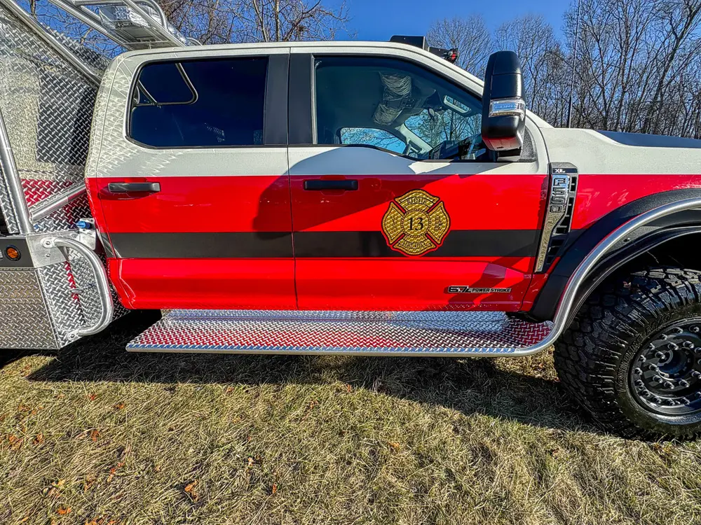 Side cab close-up showing door graphics, side step, and mirror.