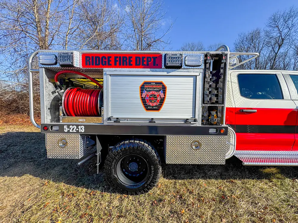 Left-side body view with roll-up compartment door and red hose reel.