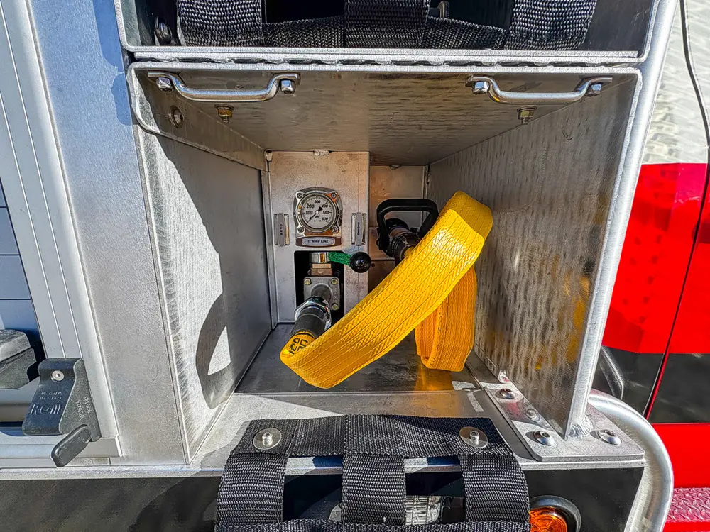 Open side compartment containing a yellow strap and pressure gauge.