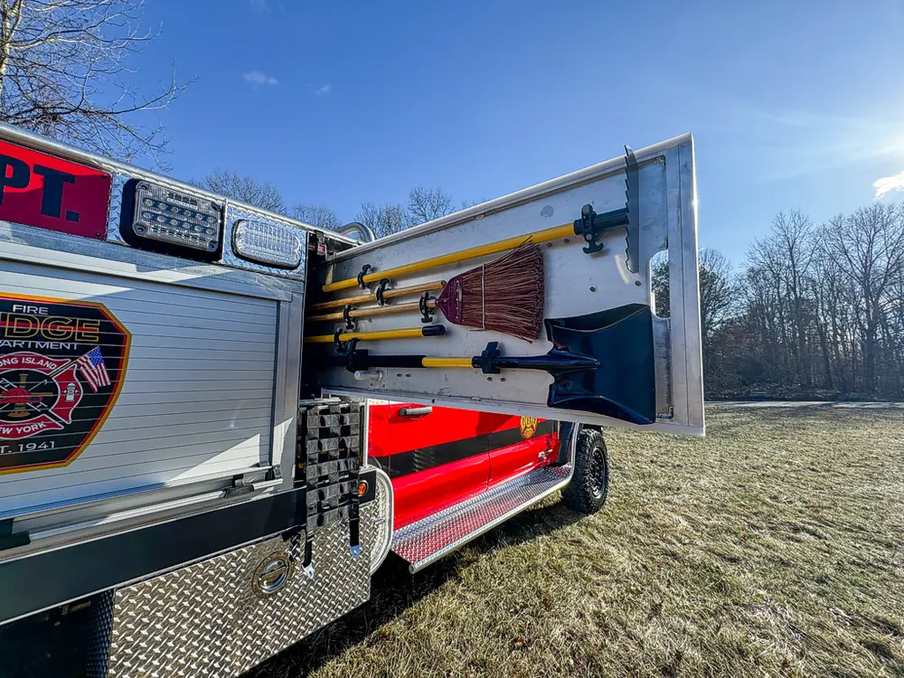 Open utility-body side compartment with fold-out door and interior hardware.