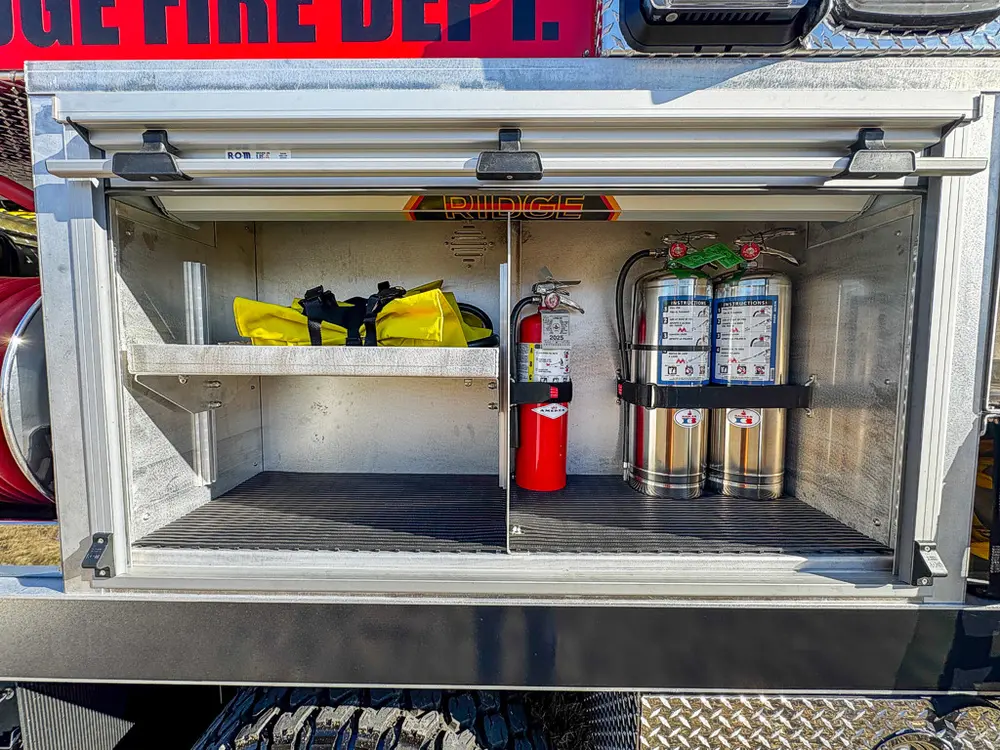 Open side storage compartment with shelves and mounted cylinders.