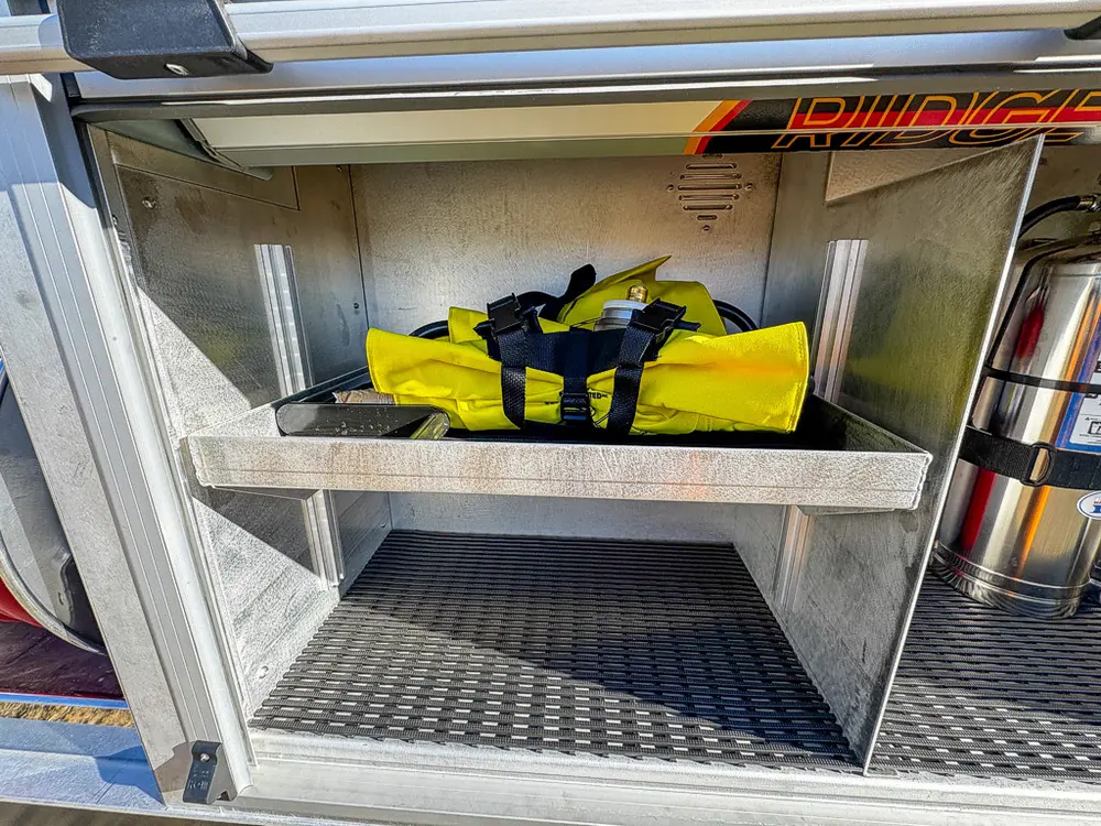 Open lower compartment with shelf and gear bag stored inside.