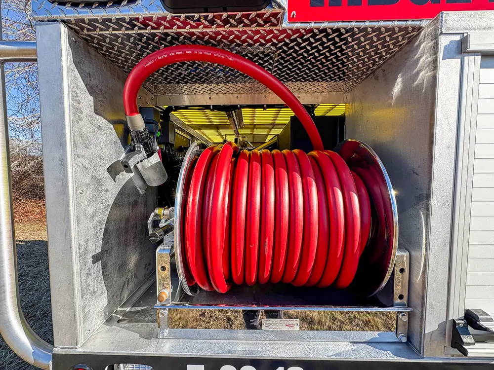 Open compartment containing a red hose reel and upper shelf.