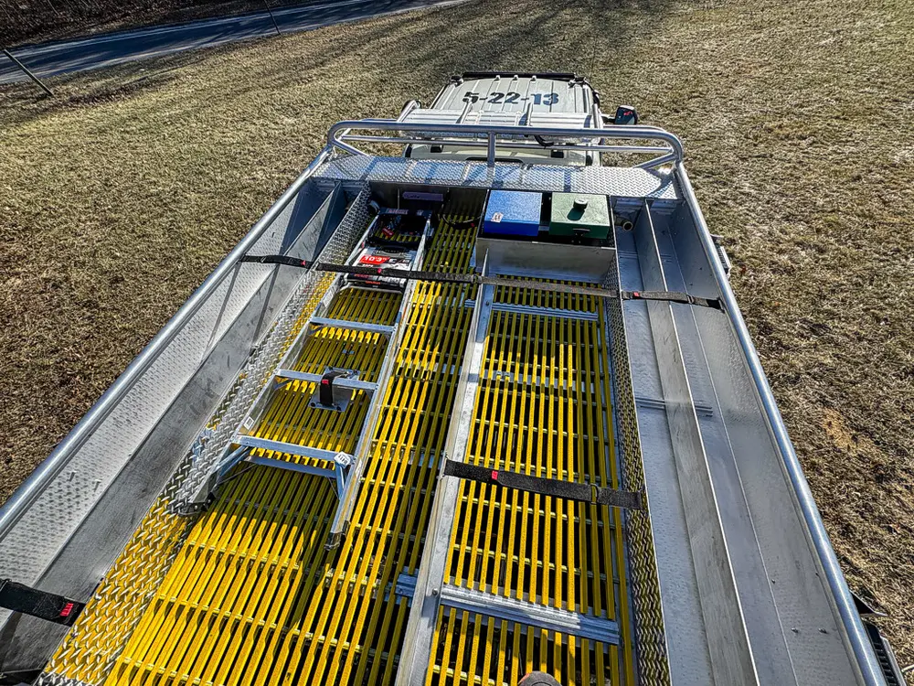 Top-deck walkway view looking rearward along yellow grated surfaces.