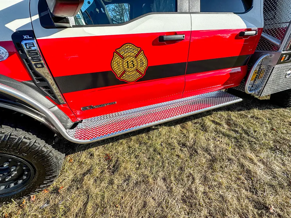 Cab side close-up with door emblem, side step, and lower rocker panel.