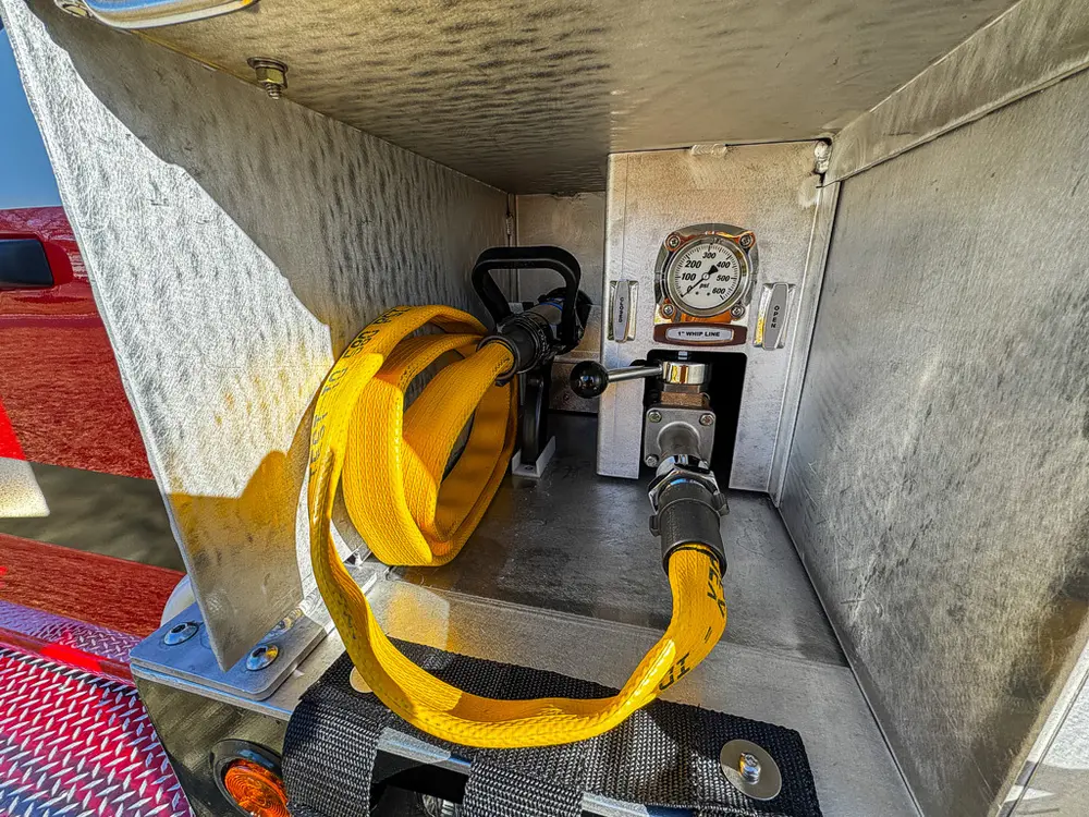 Open side compartment with yellow hose reel and pressure gauge.