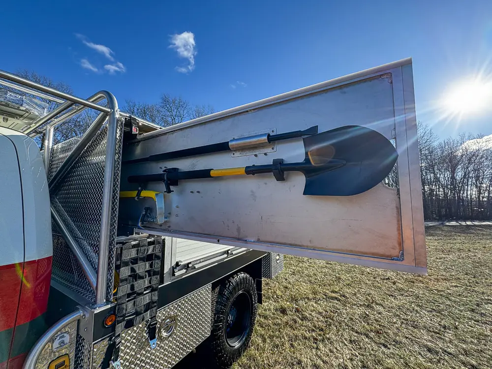 Open side compartment door with shovel mounted across the inside panel.