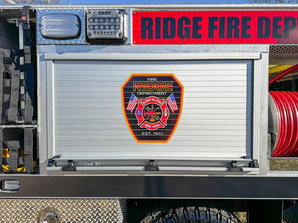 Closed roll-up compartment door with fire department emblem decal.
