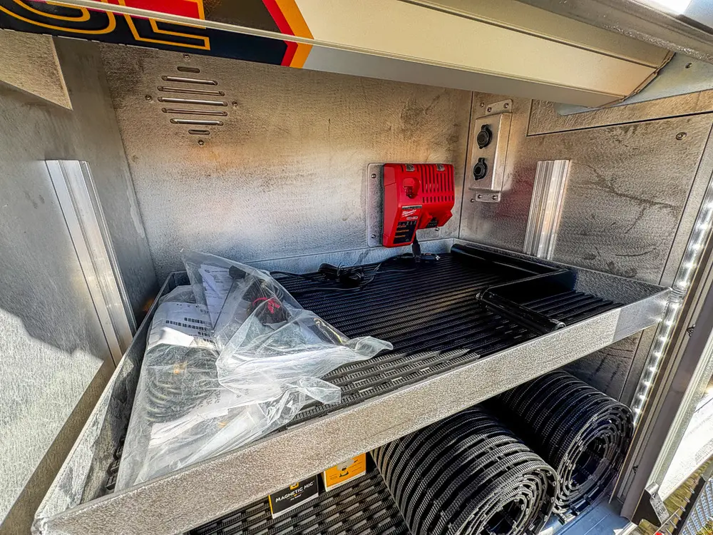 Side compartment with shelf, bagged item, and rolled floor mat.