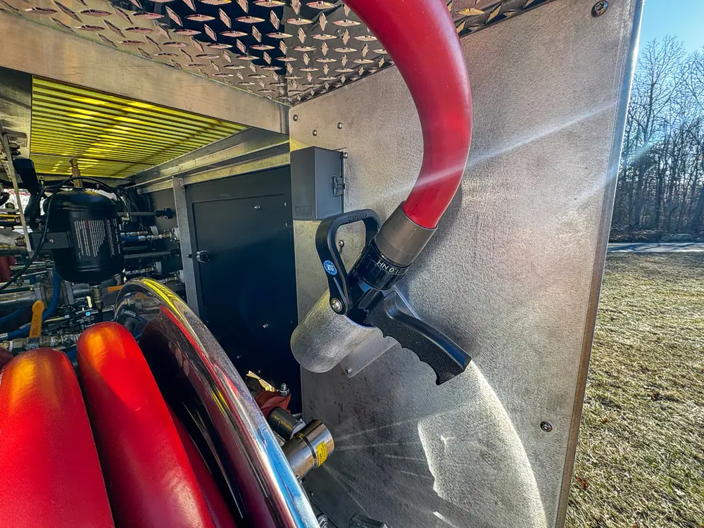 Pump area close-up with red hose, coupling, and nearby plumbing.