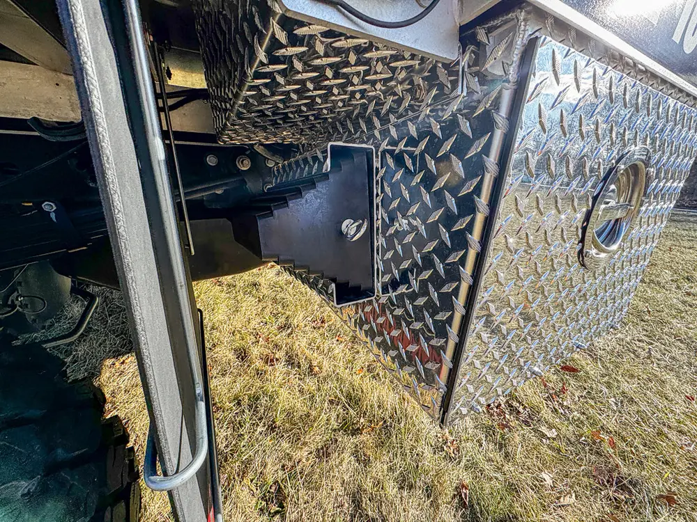 Lower side body close-up with diamond-plate compartment door and latch.