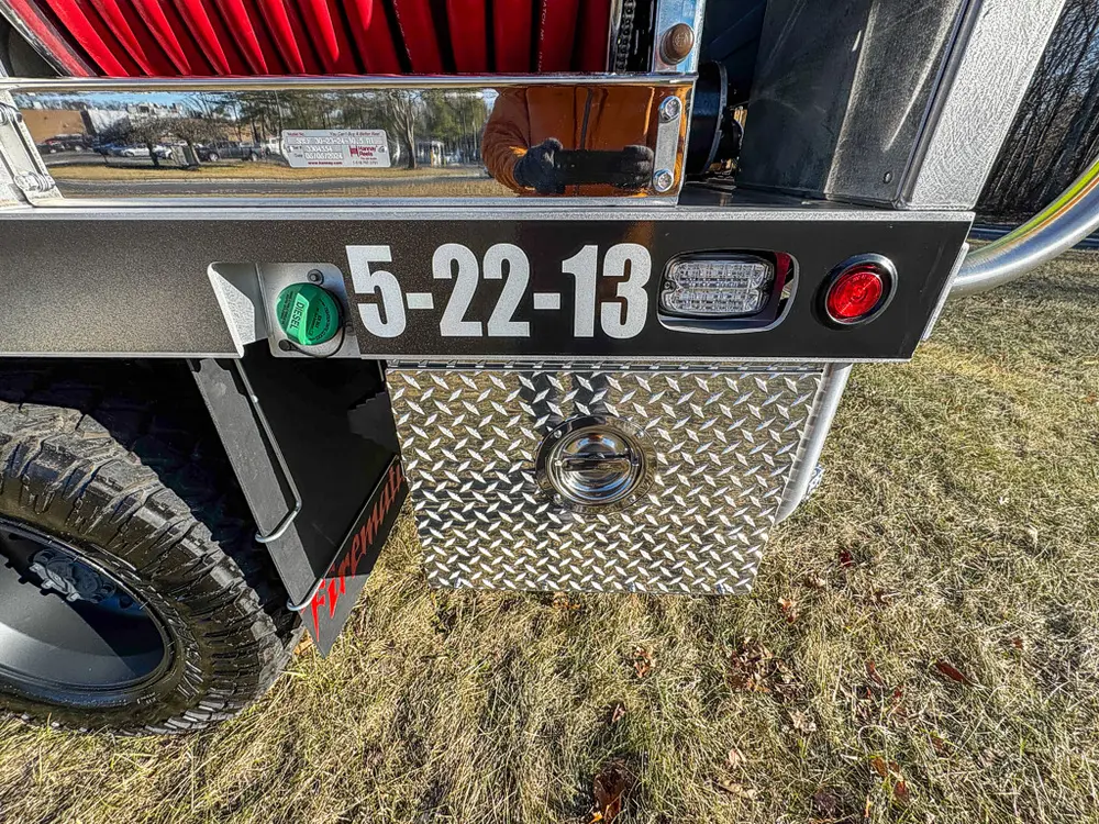 Rear lower panel close-up with plate marking, marker light, and tow ring.