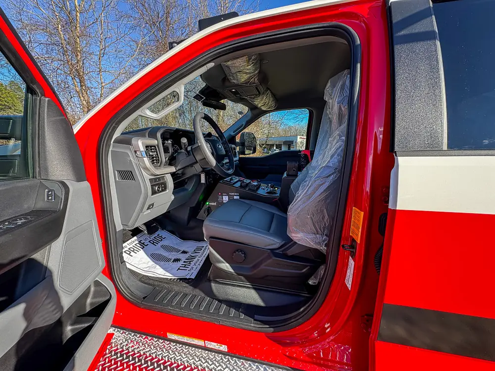 Open driver doorway showing steering wheel, seat, and dashboard controls.