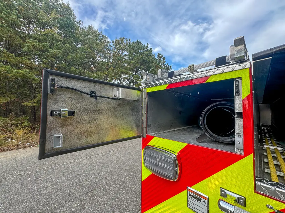 Open rear-side compartment with hose reel visible inside.