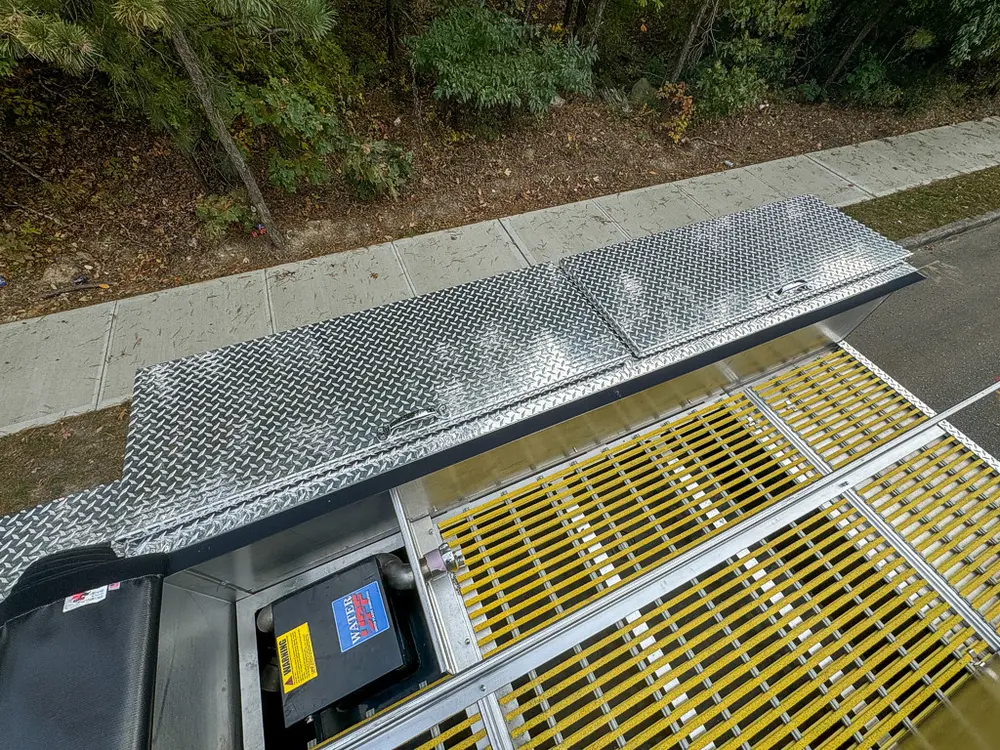 Top-side panel lifted over yellow grating and compartment access.