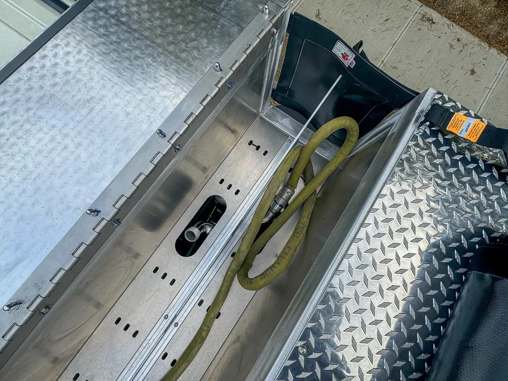 Narrow top-side trough compartment with hoses and fittings.