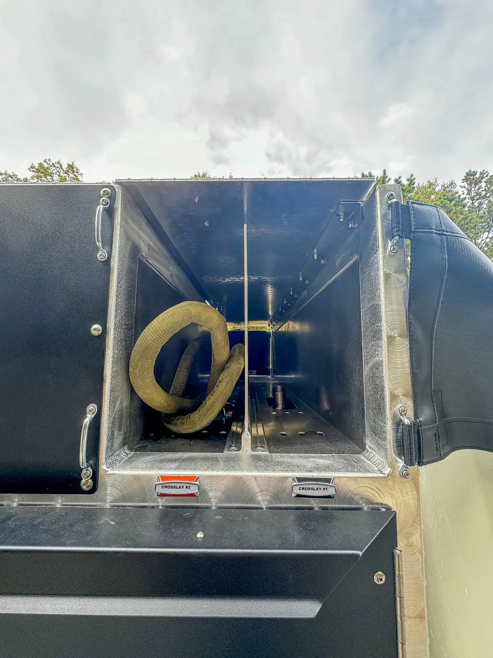 Inside top-side tube compartment showing coiled hose and fittings.