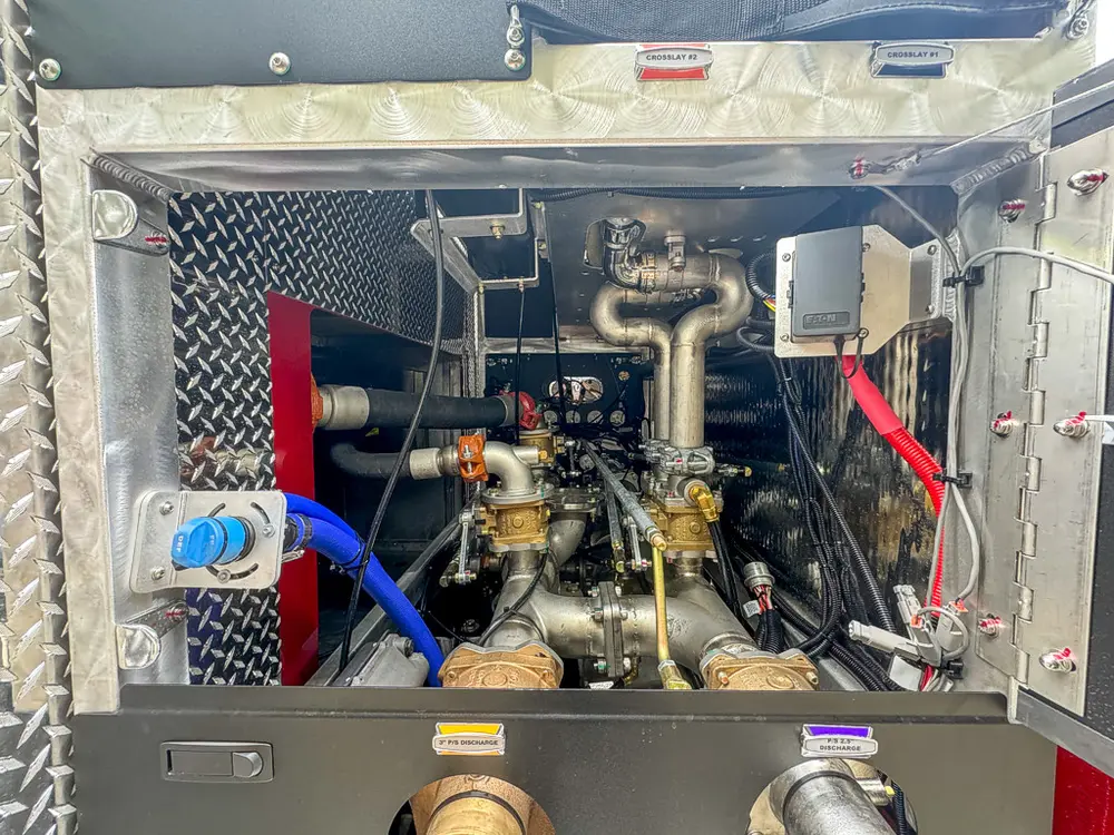 Pump compartment interior close-up with blue hoses and manifold.