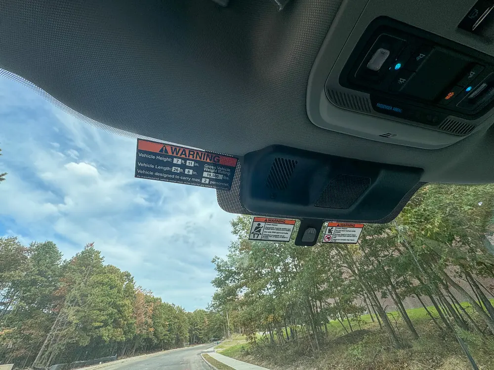Overhead console and sun visor warning labels inside cab.