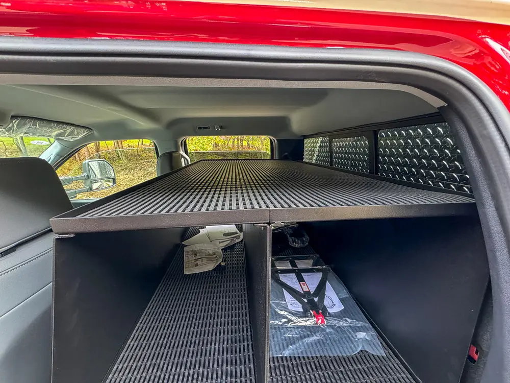 Rear shelf unit close-up behind front seats with mounted electronics.