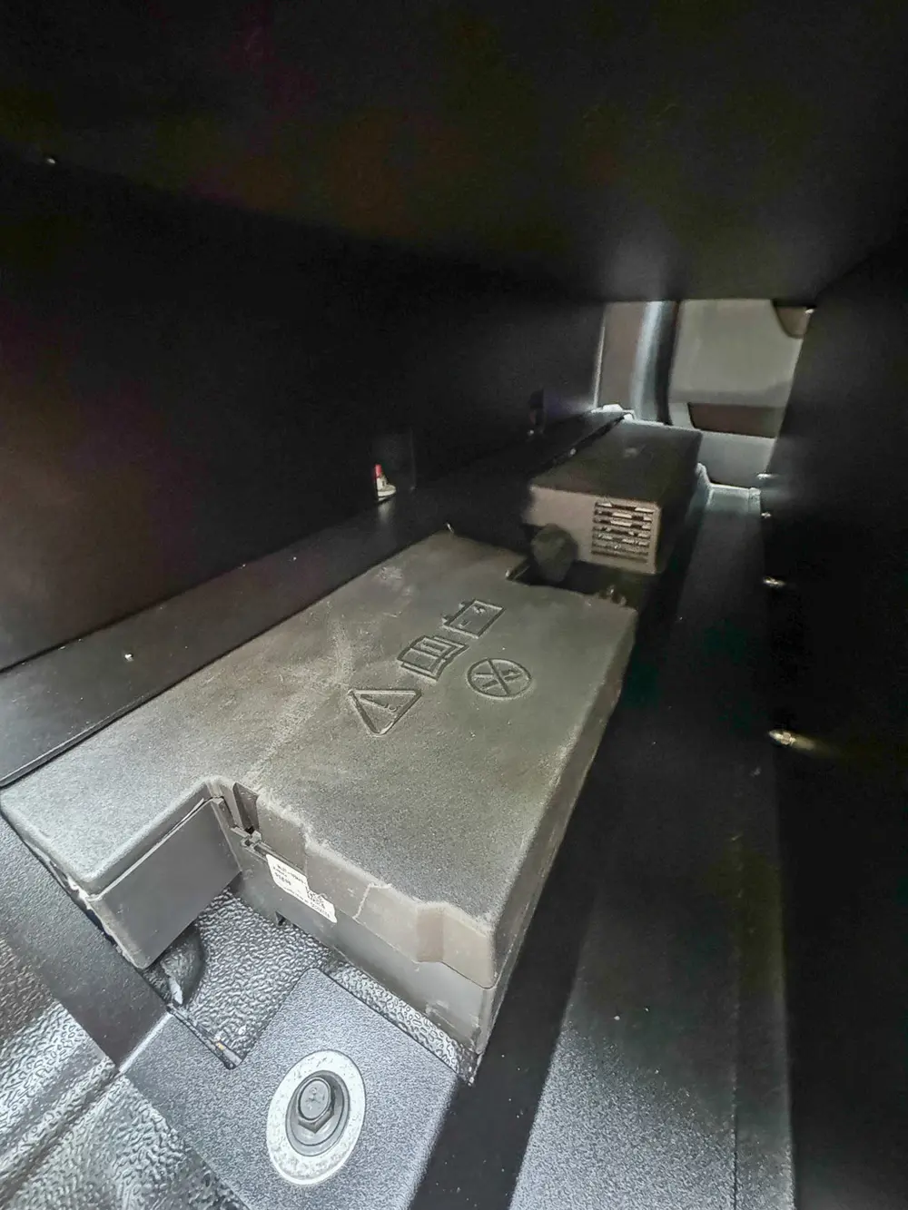 Lower rear compartment floor close-up with small warning stickers.