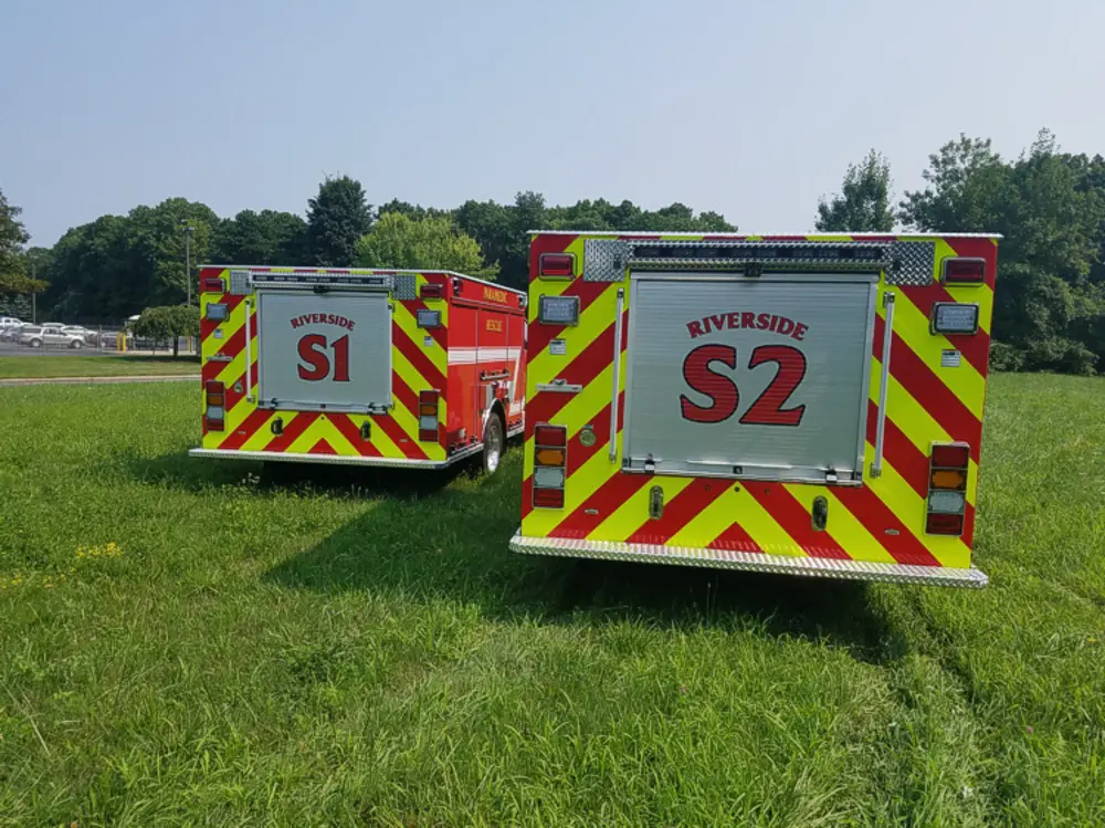 Exterior view of small fire truck showing cab, body compartments, and wheel/tire area.