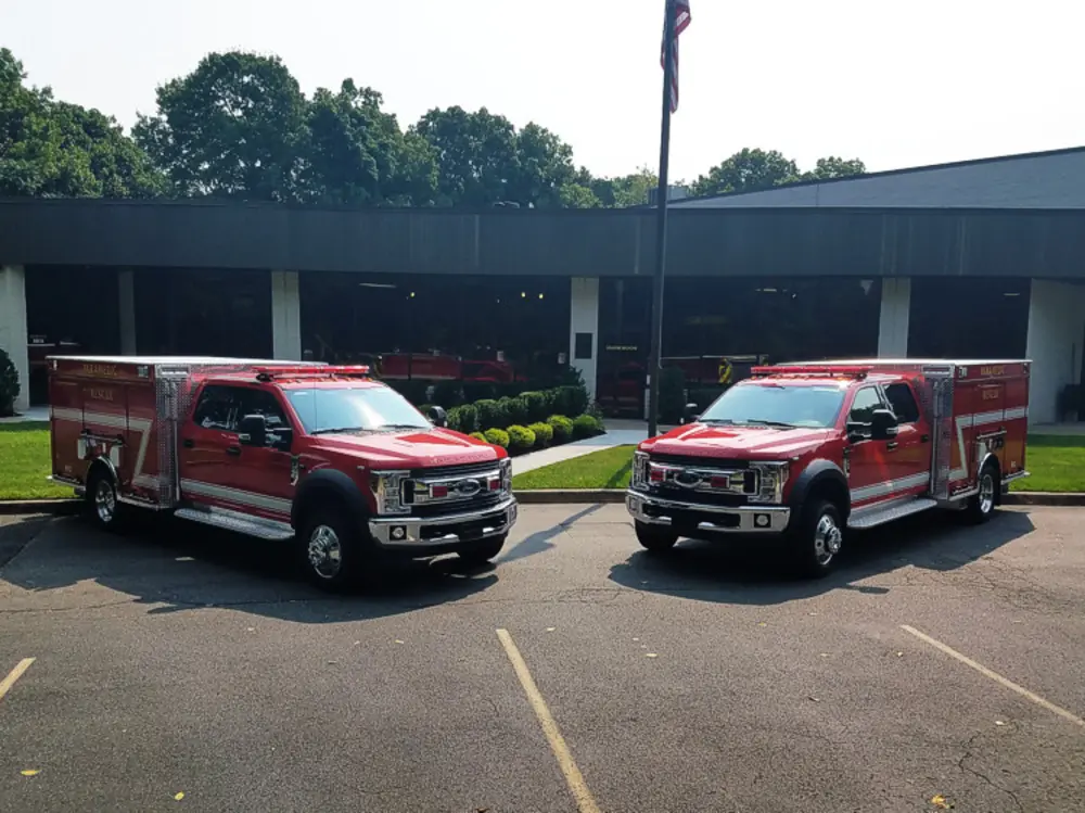 Exterior view of small fire truck showing cab, body compartments, and wheel/tire area.