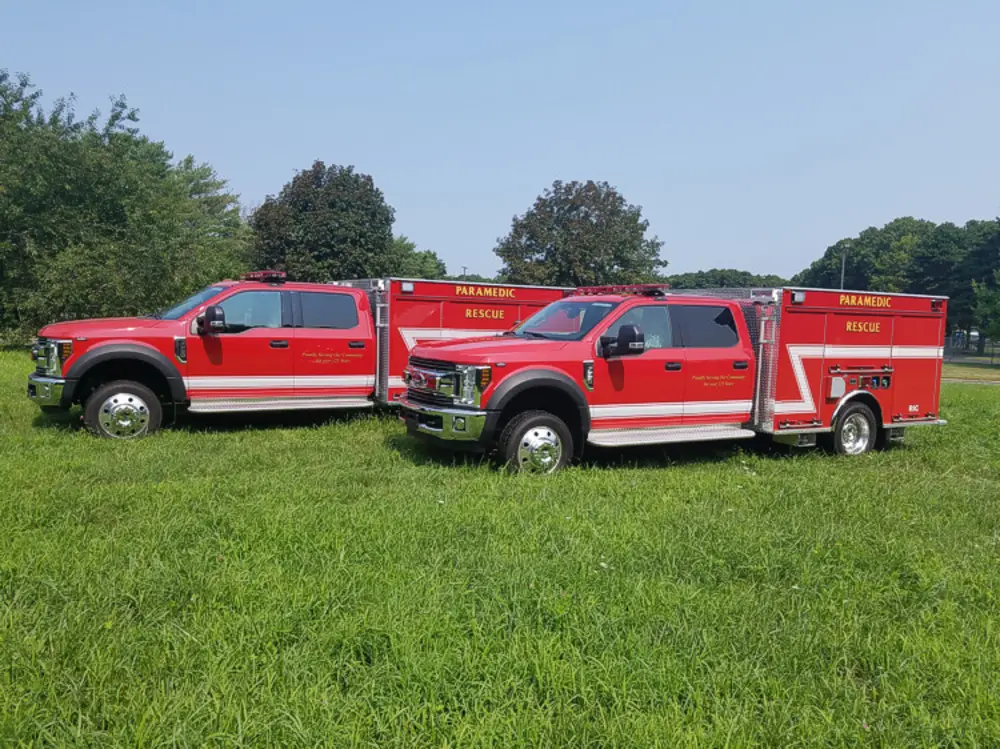 Exterior view of small fire truck showing cab, body compartments, and wheel/tire area.