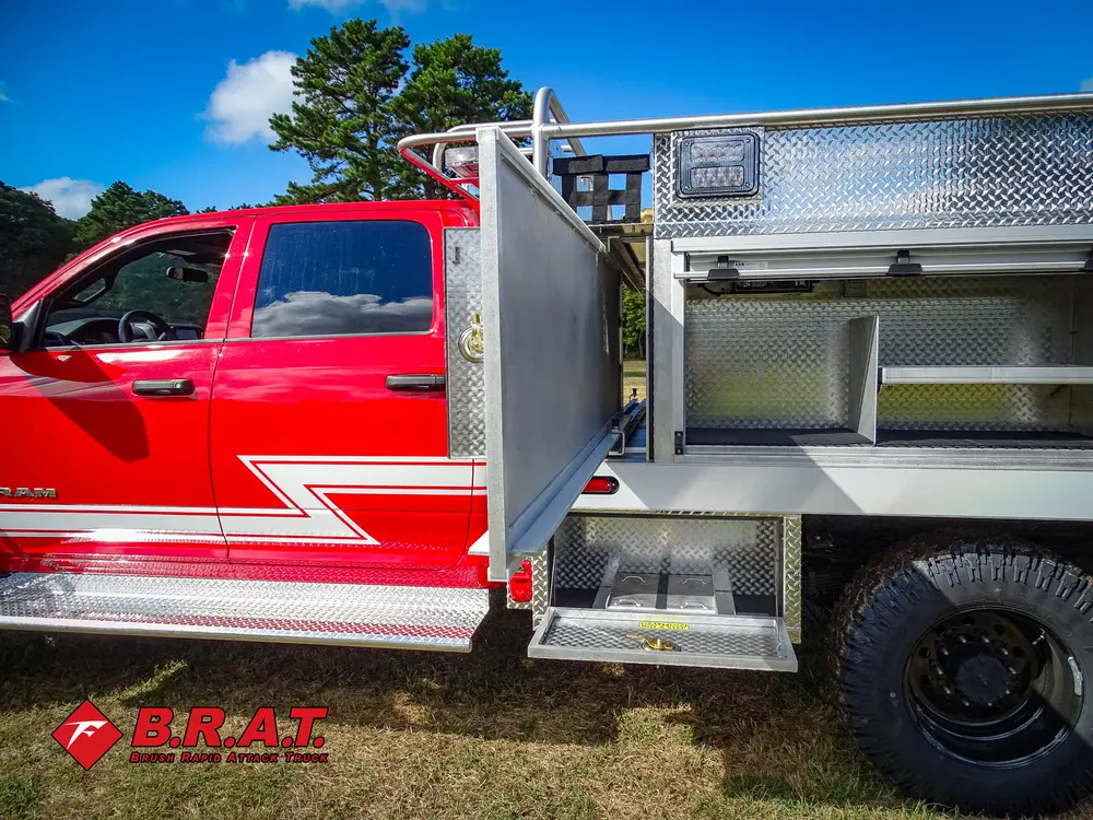 Exterior view of small fire truck showing cab, body compartments, and wheel/tire area.