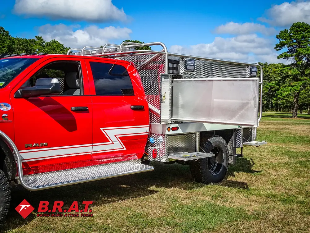 Exterior view of small fire truck showing cab, body compartments, and wheel/tire area.