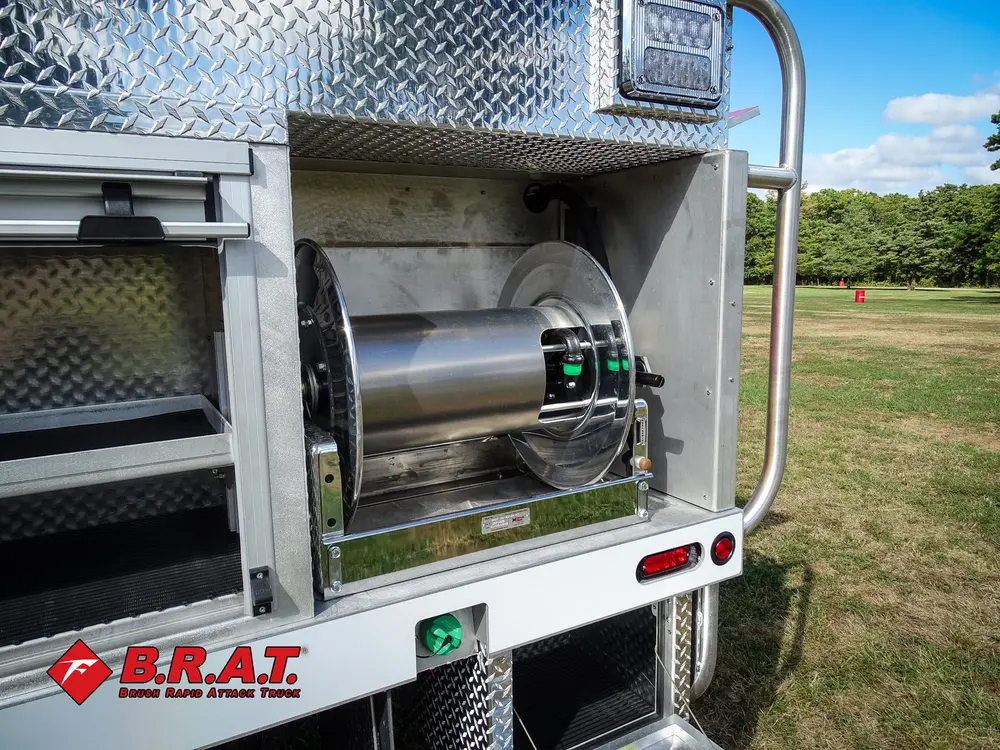 Exterior view of small fire truck showing cab, body compartments, and wheel/tire area.