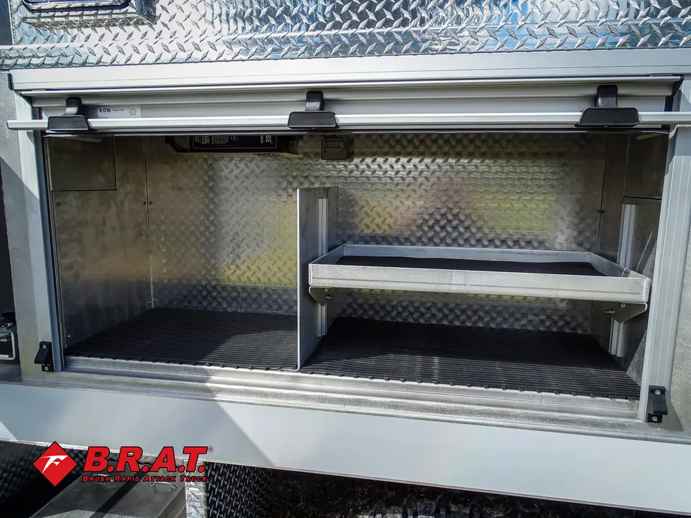 Exterior view of small fire truck showing cab, body compartments, and wheel/tire area.