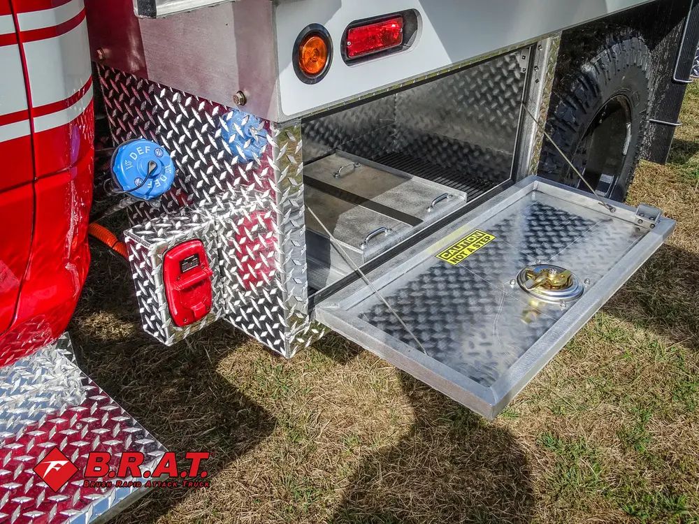 Exterior view of small fire truck showing cab, body compartments, and wheel/tire area.