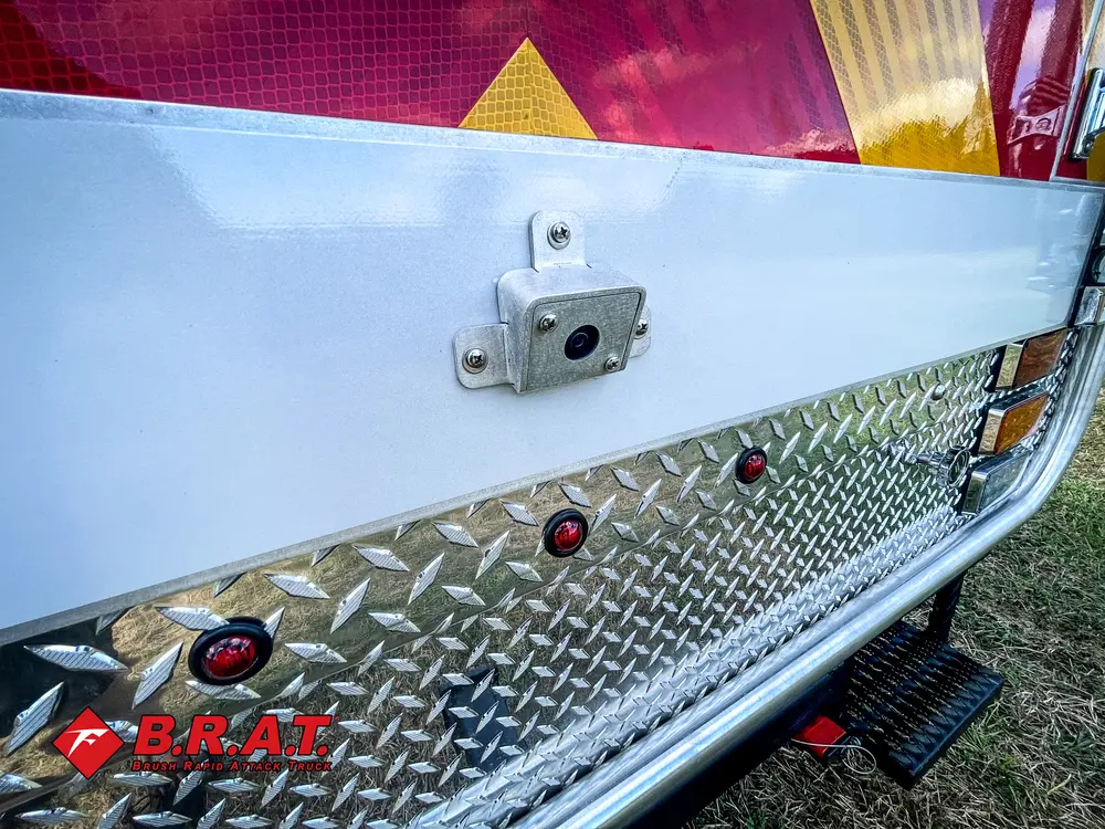 Exterior view of small fire truck showing cab, body compartments, and wheel/tire area.