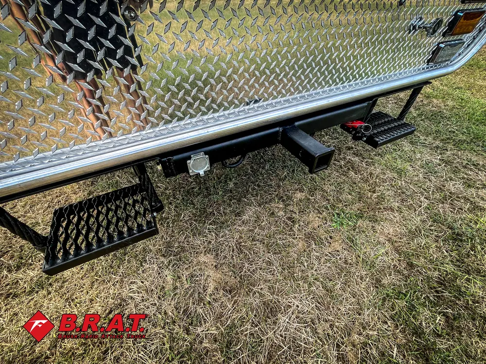 Exterior view of small fire truck showing cab, body compartments, and wheel/tire area.