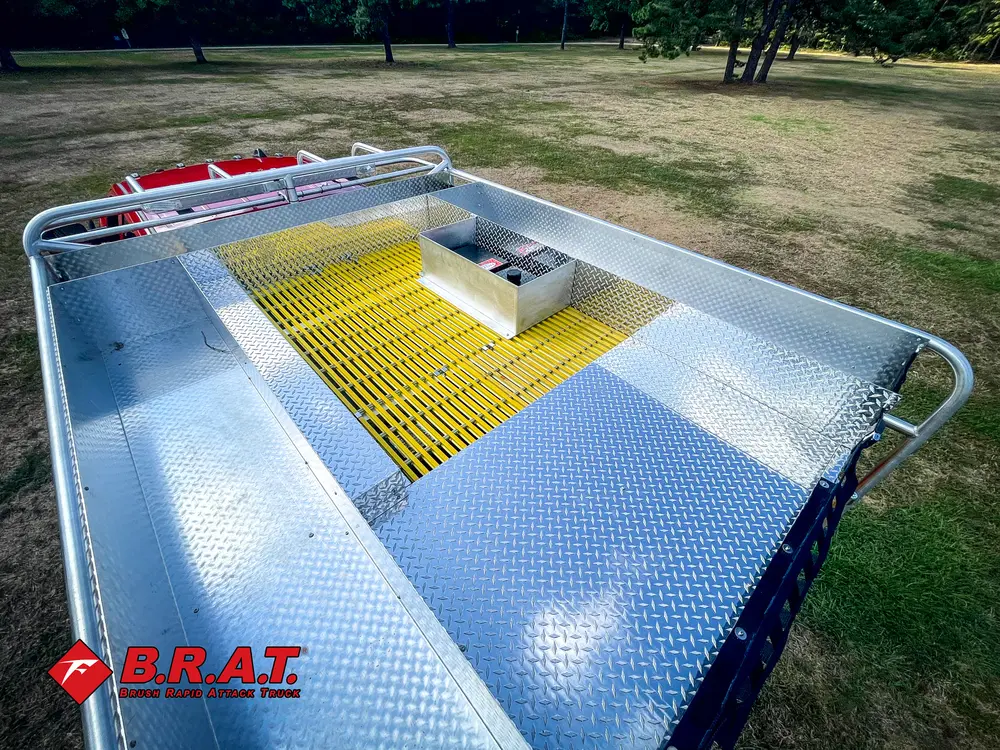 Exterior view of small fire truck showing cab, body compartments, and wheel/tire area.