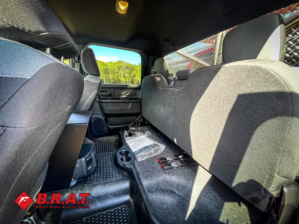 Exterior view of small fire truck showing cab, body compartments, and wheel/tire area.