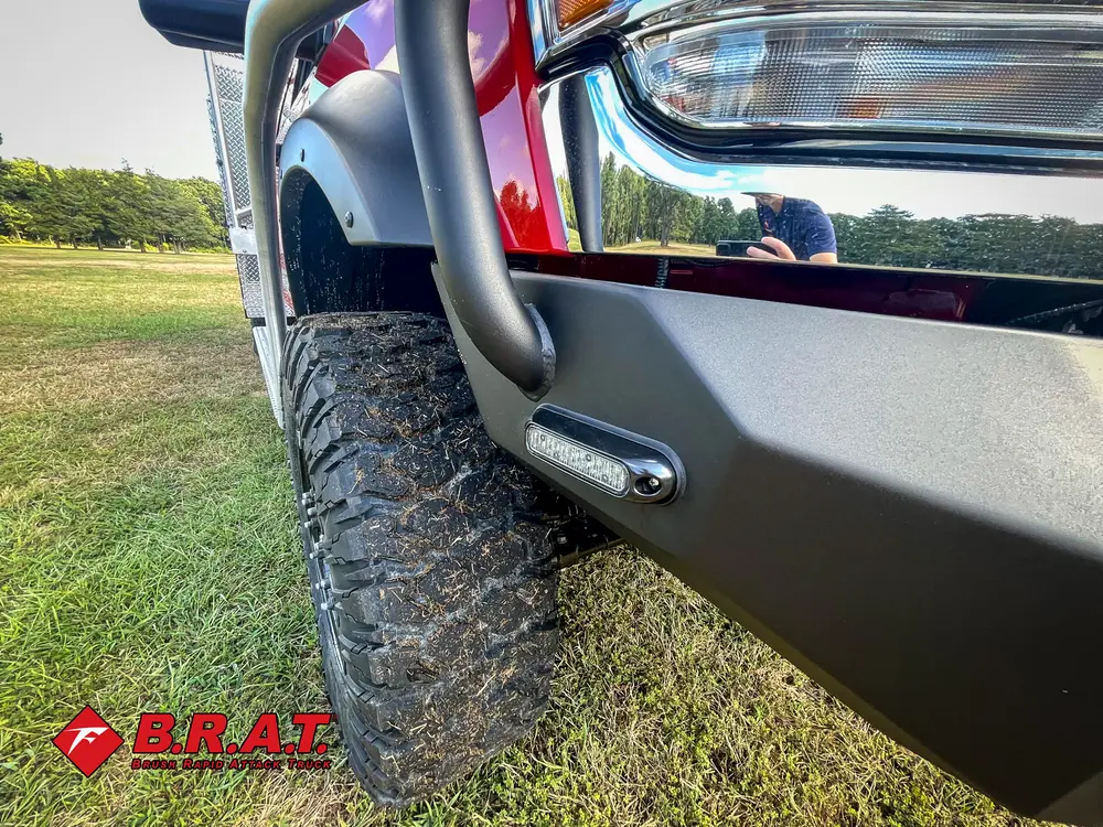 Exterior view of small fire truck showing cab, body compartments, and wheel/tire area.