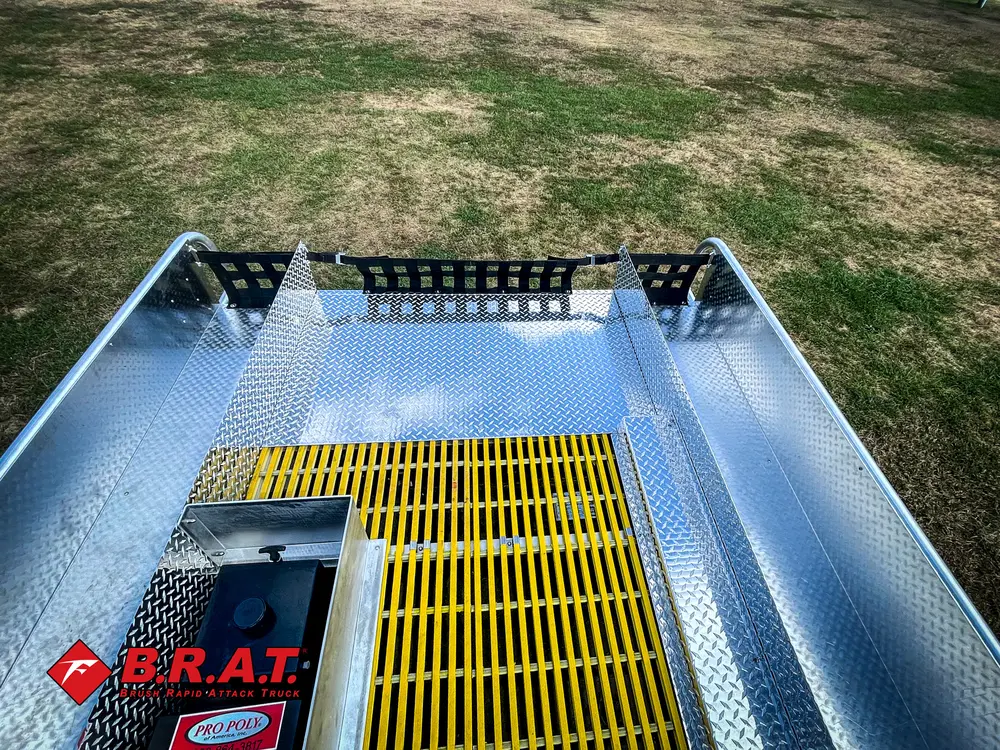 Exterior view of small fire truck showing cab, body compartments, and wheel/tire area.