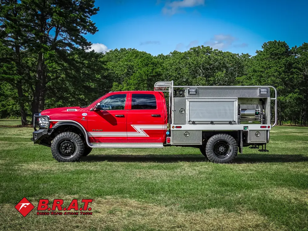 Exterior view of small fire truck showing cab, body compartments, and wheel/tire area.