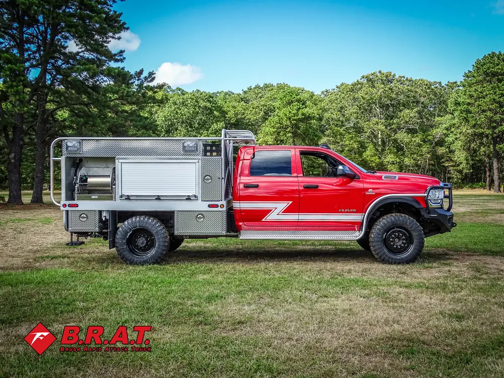 Exterior view of small fire truck showing cab, body compartments, and wheel/tire area.