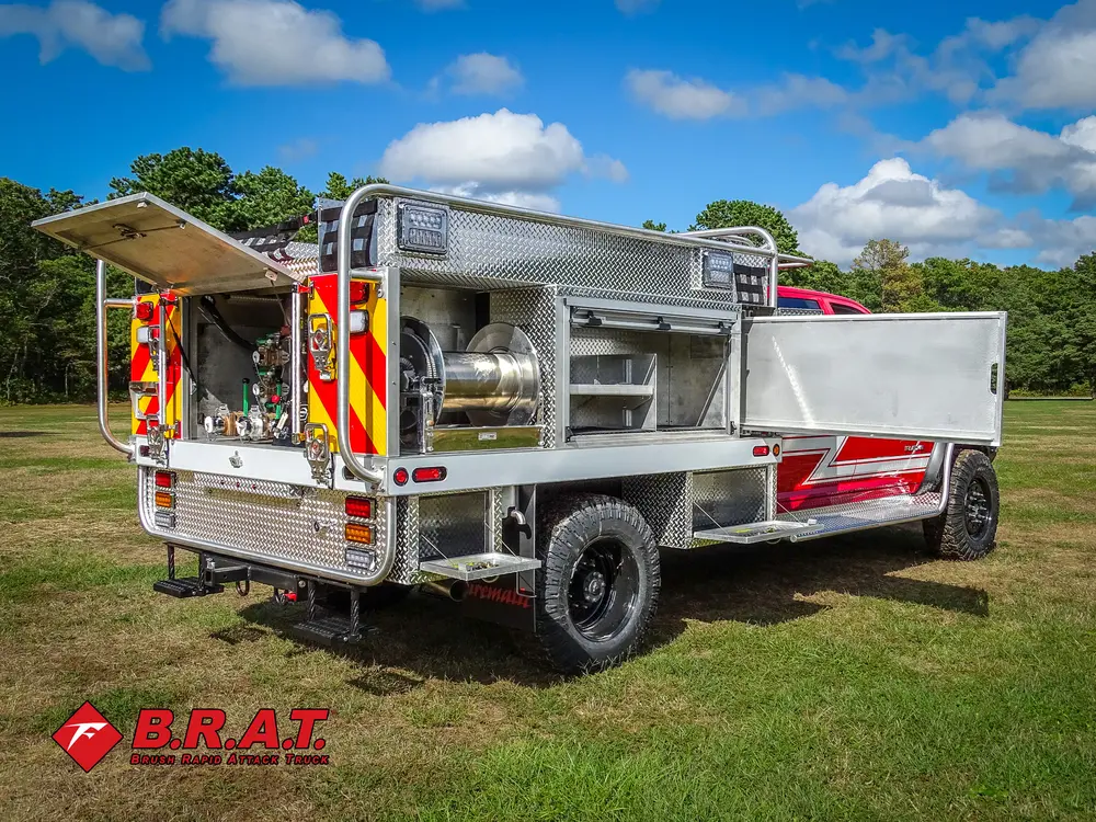 Exterior view of small fire truck showing cab, body compartments, and wheel/tire area.