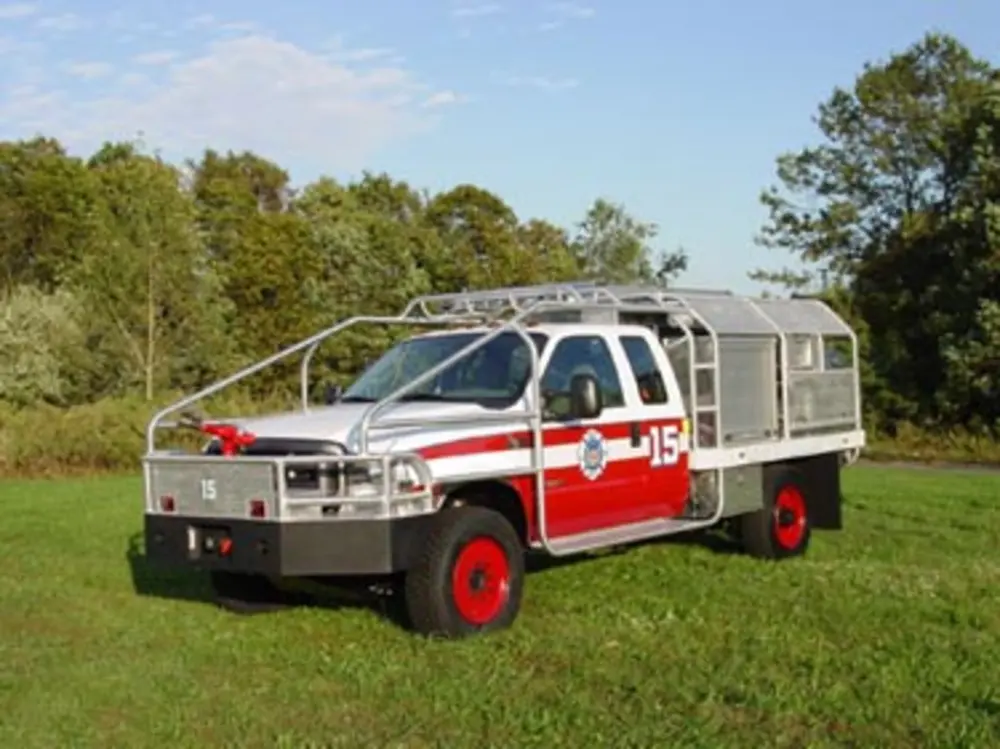 Exterior view of small fire truck showing cab, body compartments, and wheel/tire area.