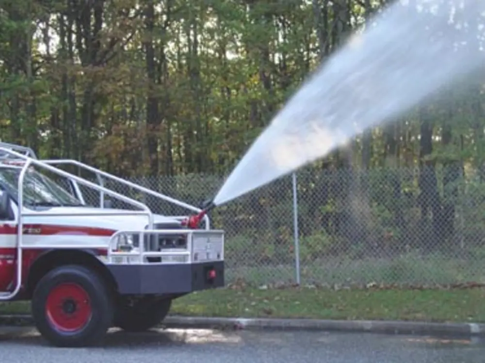 Exterior view of small fire truck showing cab, body compartments, and wheel/tire area.