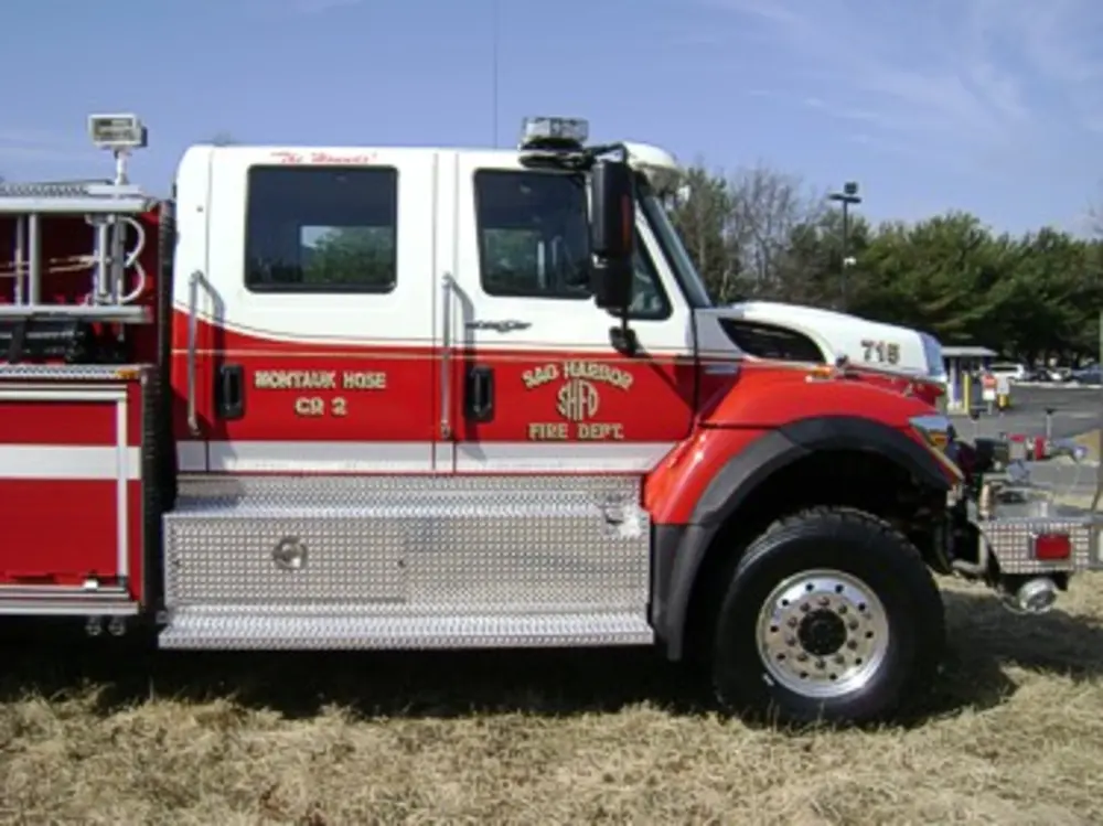 Exterior view of small fire truck showing cab, body compartments, and wheel/tire area.