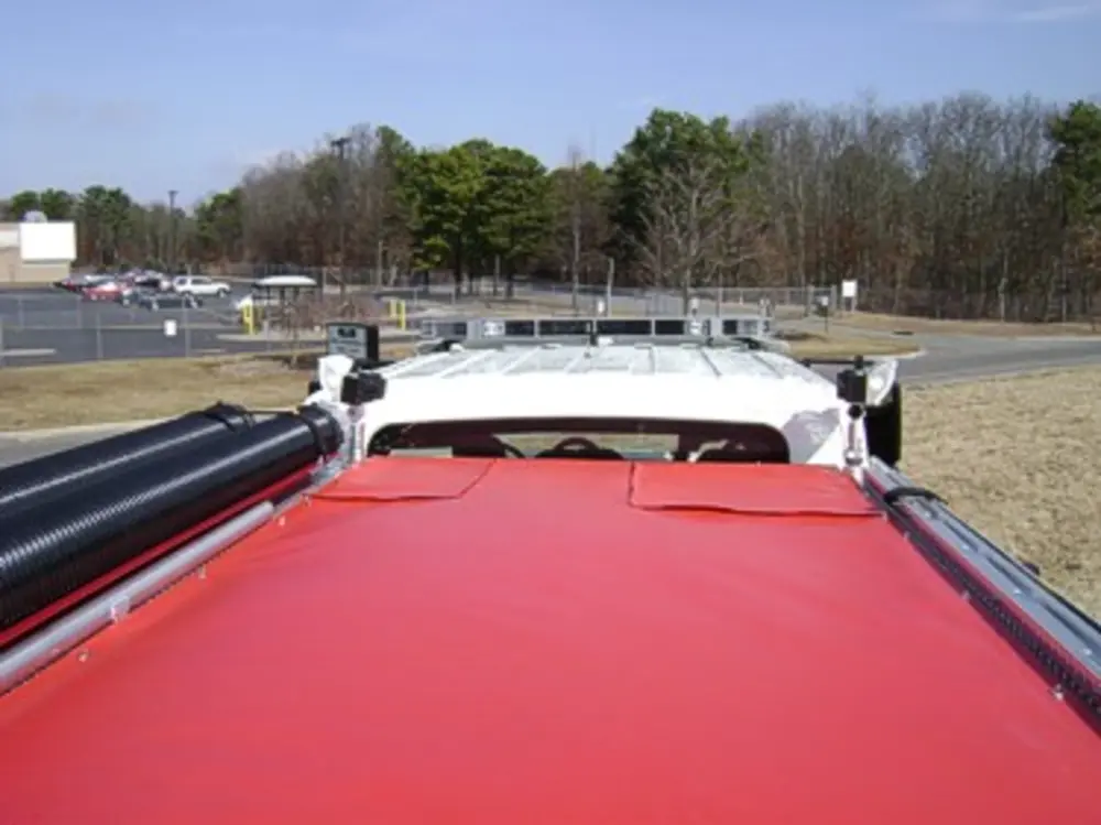 Exterior view of small fire truck showing cab, body compartments, and wheel/tire area.